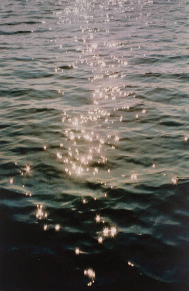 De glinstering van de ondergaande zon op een kabbelende zee.